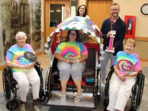 St. Clare Meadows' rickshaws were named the top non-commercial entry in the July 20 Big Top Parade. The Baraboo assisted living facility received a trophy and $100 in Chamber Bucks. Pictured celebrating this triumph are (from left) resident Vi Tully, Activity Coordinator Emily Bowen (seated), Director of Organization Advancement Samantha Machovec, Baraboo Area Chamber of Commerce Executive Director Darren Hornby, and resident Dorothy Dorner.