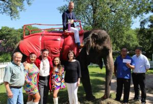 Circus World's elephants were named the top overall entry in the July 20 Big Top Parade, wining a trophy and $100 in Chamber Bucks. Shown celebrating the victory are (from left) parade co-chair Doug Hill; Circus World performers Adriana Poema-Parker, Dave SaLoutos and Tatiana Fusco-Combs; parade committee member Susan Walsh; Baraboo Area Chamber of Commerce Executive Director Darren Hornby atop Tracy the elephant; trainer Armando Loyal; and Circus World Executive Director Scott O'Donnell.