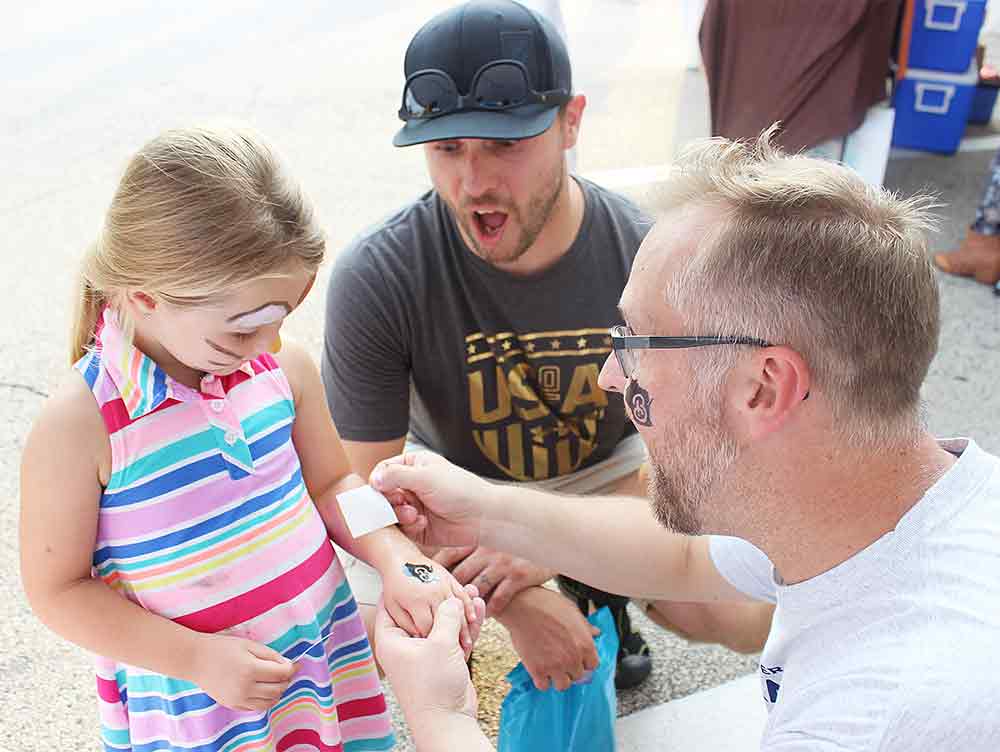 Chamber executive giving girl a temporary tattoo